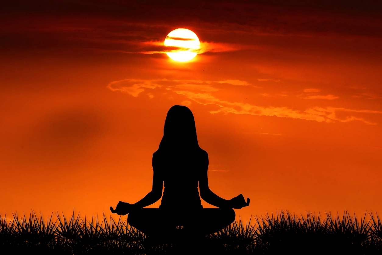 A woman sitting in the grass with her legs crossed.